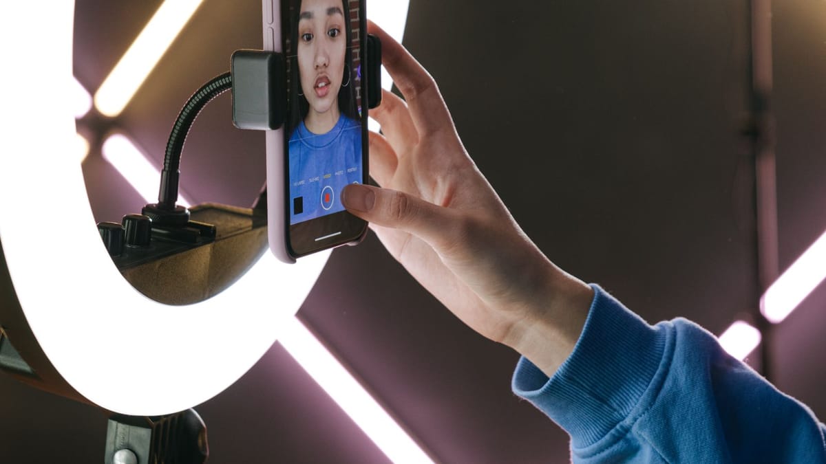 Junge Frau filmt sich mit dem Handy und Ringlicht