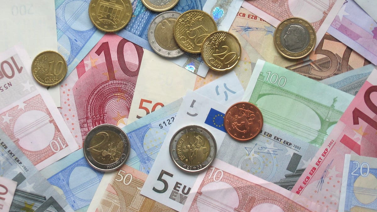 Notas e moedas de euro espalhadas sobre uma mesa